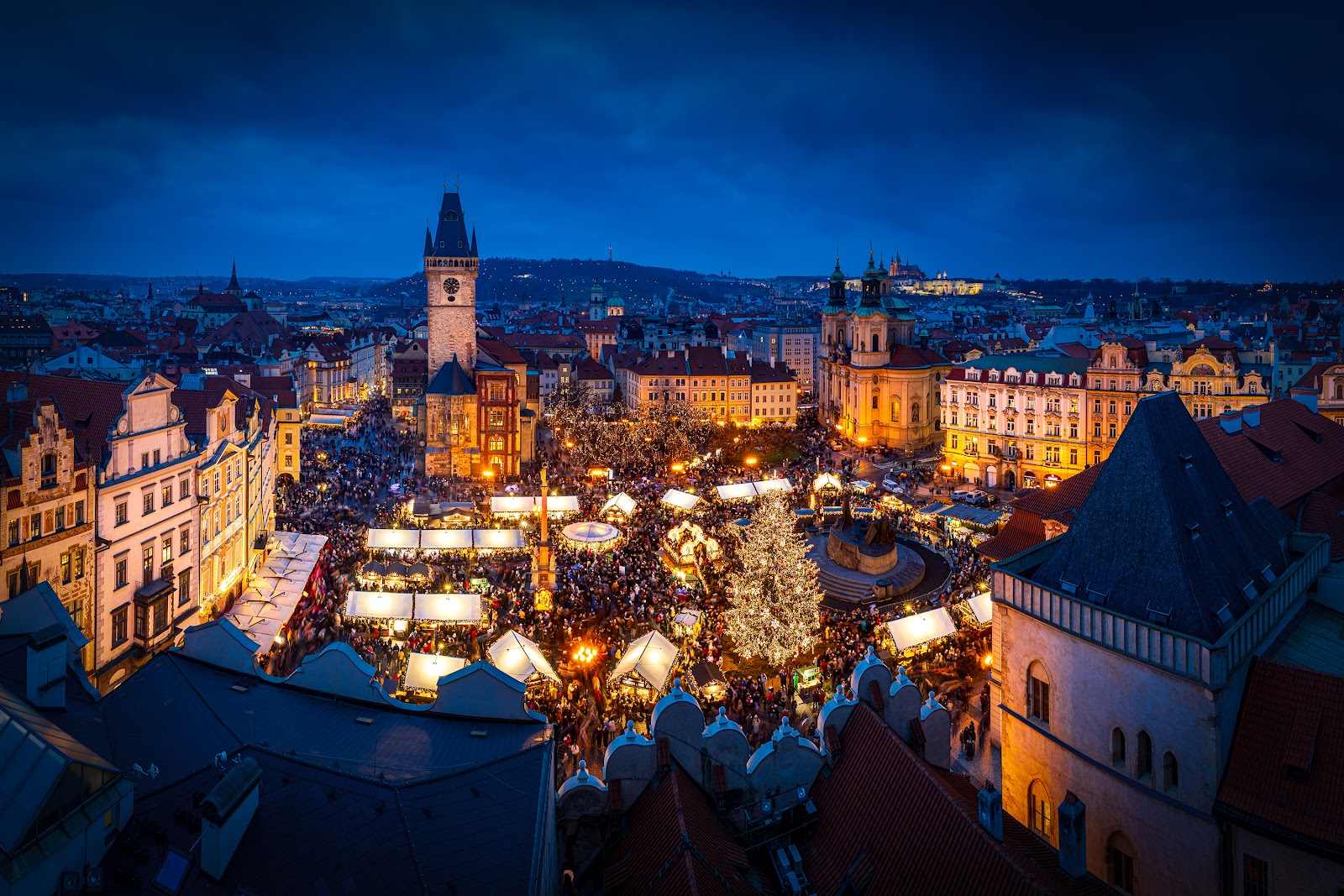 Blick von oben auf einen beleuchteten Weihnachtsbaum auf einem vollen Platz